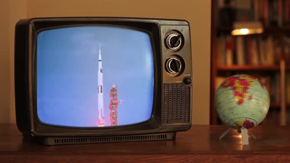 Color Footage of the 1969 Apollo 11 Launch on a Retro TV near a Globe Map. alt