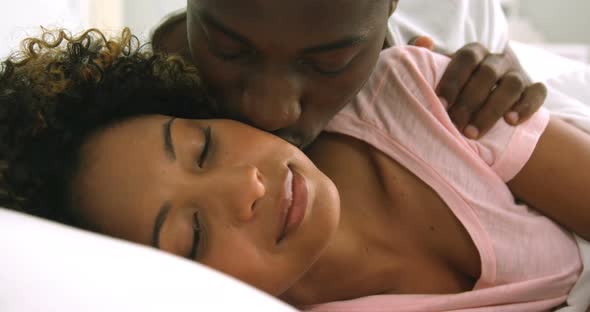 Young couple embracing while lying on bed alt