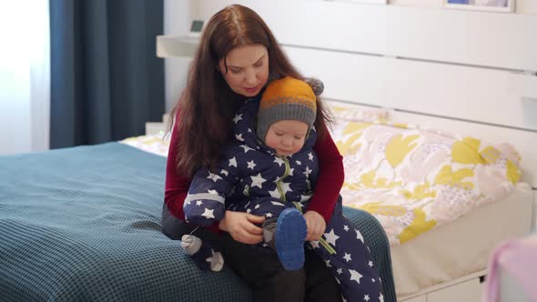 Mother Dressing the Baby in Warm Clothes for a Walk in Winter alt