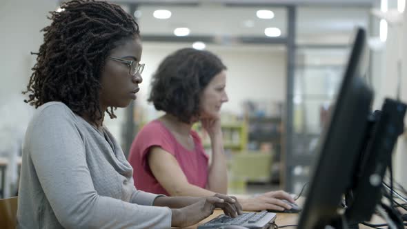 Side View of Two Women Working with Computers alt