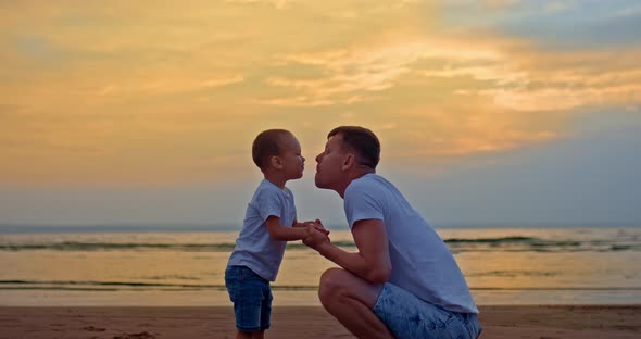 Portrait of a Loving Dad Playing with His Son on the Seashore Kissing Him and Hugging Him