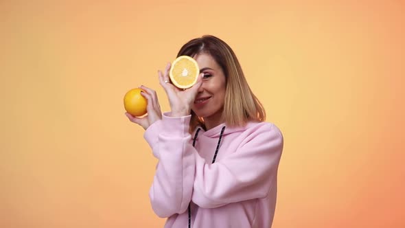 Woman in Casual Pink Clothes Holding Oranges and Dancing