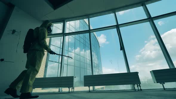 Person in Hazmat Disinfects a Room. alt