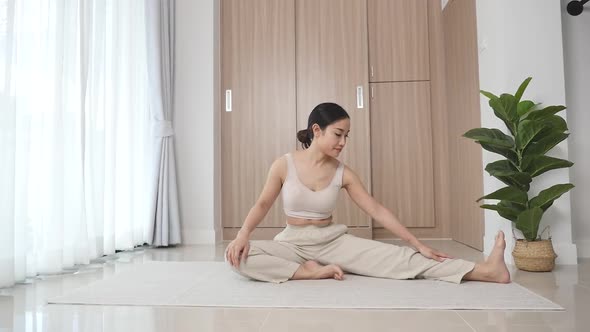An athletic woman sits on the floor by a large window during her morning yoga  alt
