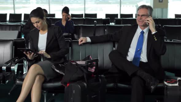 Business people wait in airport lobby alt