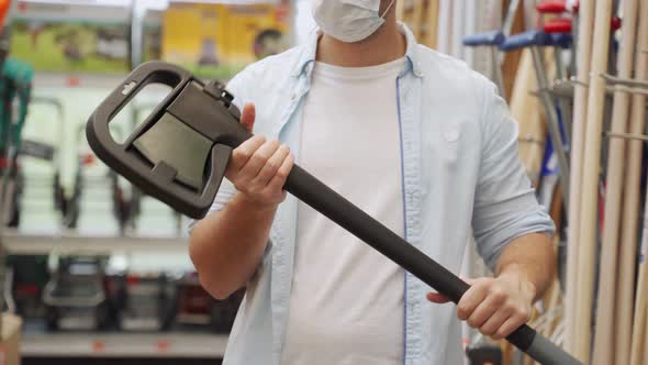 Man in a Medical Mask Picks Up an Axe in the Construction Department of a Shopping Center alt