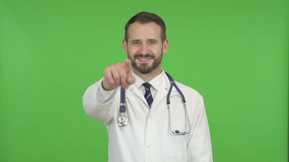 Cheerful Doctor Pointing Finger and Inviting Against Chroma Key alt