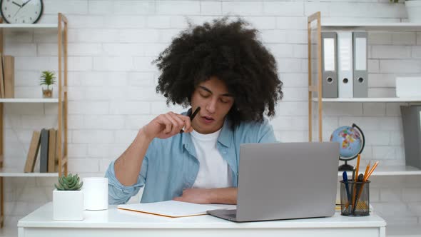 Pensive Student Guy Learning Taking Notes Sitting At Laptop Indoors alt
