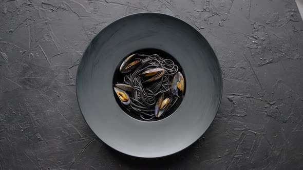 Seafood Black Spaghetti Pasta with Clams Served on Black Plate on Dark Stone alt