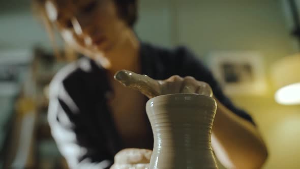 Young Female Potter Gently Pulls the Walls of a Clay Vessel on a Potter's Wheel
