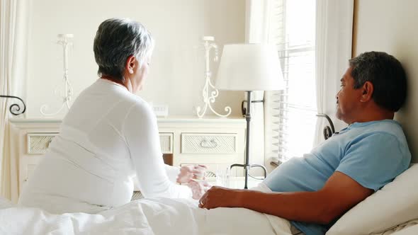 Senior woman giving medicine to senior man 4k alt