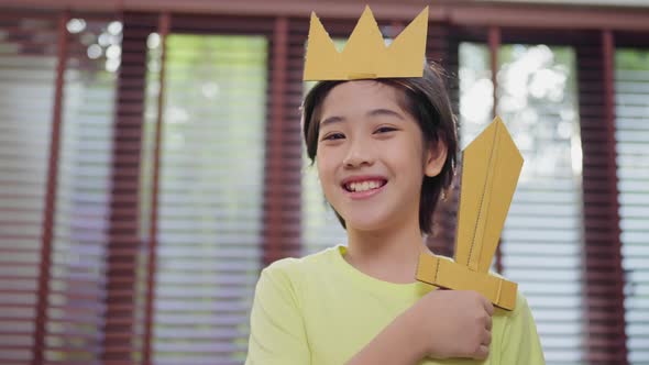 asian little prince child boy play role,young boy playing as king hand hold paper sword smiling