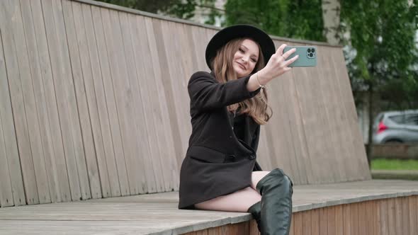 A Young Woman Takes a Selfie on a Smartphone
