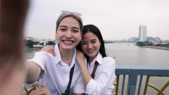 Happy Asian lesbian couples using smartphone video chatting with friends travel in Thailand.