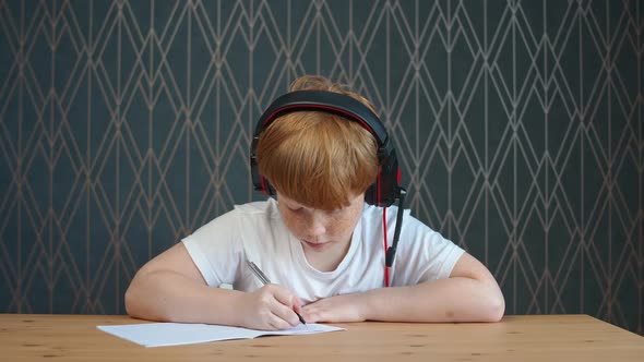 Homeschooling Online By Videocall Redhaired Teen Boy Sitting at Workplace in Living Room and Uses a alt