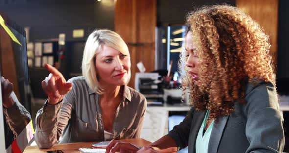 Businesswoman interacting with coworkers while working on computer alt
