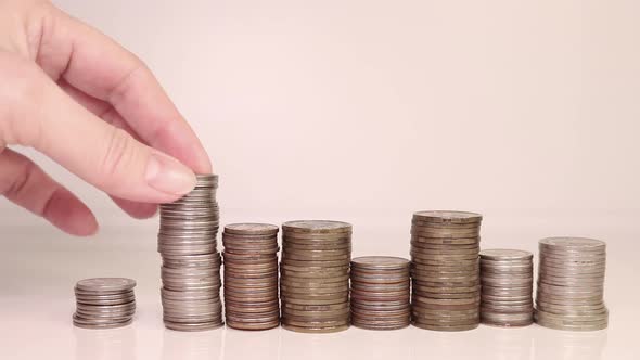 A woman's hand puts coins in a column. Investment concept. Metallic currency. alt