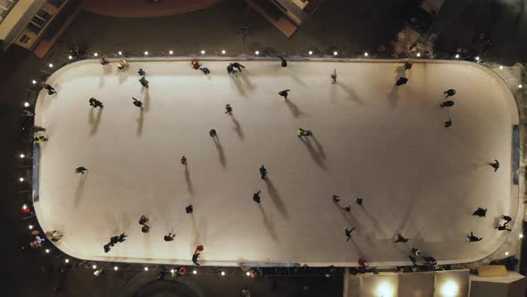 People Are Skating on Ice Rink in the Evening. Aerial Vertical Top-down View