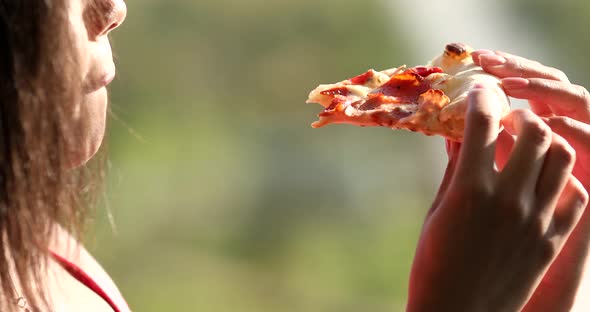 Close up portrait of young African woman eating slice of pizza. alt