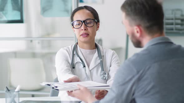 Positive Female Doctor Shaking Hands with Male Patient after Consultation alt
