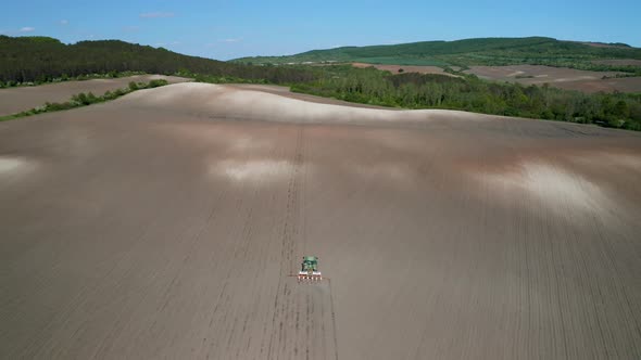 Field with picturesque hills and a moving tractor alt