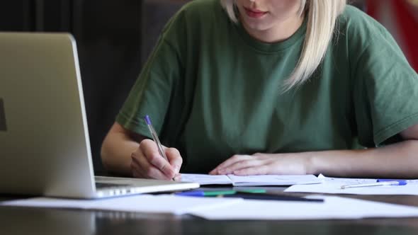 Blonde girl working with notebook at home as freelancer alt