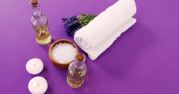 Sea salt in wooden bowl, towel, oil, candle and flowers alt