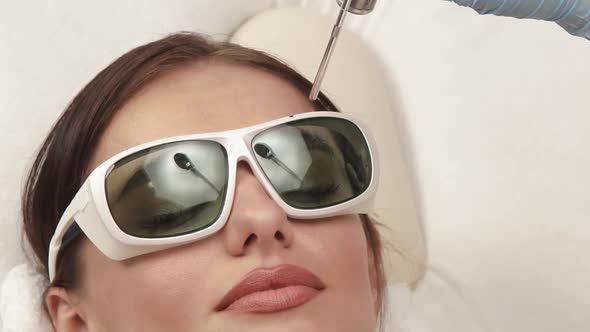 Close-up of Woman Having Facial Procedures in Protection Glasses alt