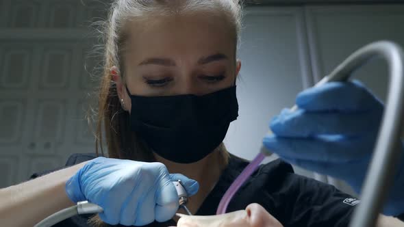 Young Female Dentist in Blue Latex Gloves Brushing the Patient's Teeth with a Jet of Water and a