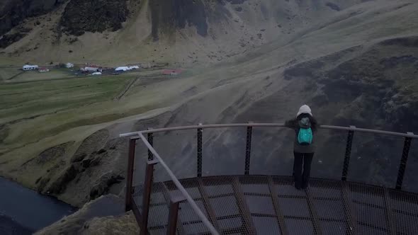 Girl standing in front of a cliff with waterfall