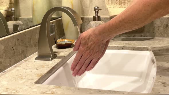 Woman Washing Hands in Bathroom Sink