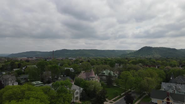 Panoramic view over midwest community with historic homes, mountains covered in trees seen.