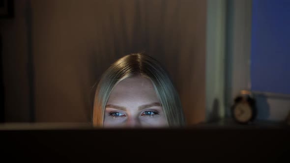 Woman Peeking Out Computer Monitor at Night alt