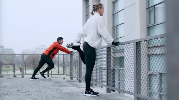 Two athletes doing warm up stretches in winter before training alt