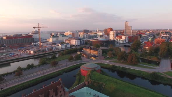 Aerial view flying over Malmo Castle and city at sunset