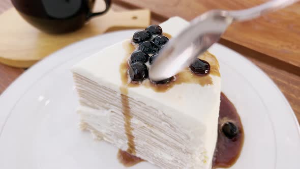 Closeup of a Man with a Teaspoon Breaks Off a Piece of Salty White Cake with Berries alt