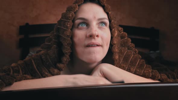 Girl Lying on Bed Watches TV and Switches Channels with Remote Control Closeup alt