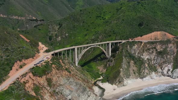 Wide aerial view of Bixby Creek Bridge on a sunny summer day in Big Sur California with the white sa alt