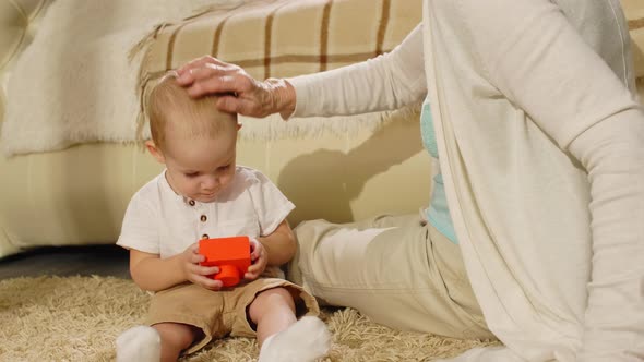 Grandmother Caressing Little Grandson while Playing at Home