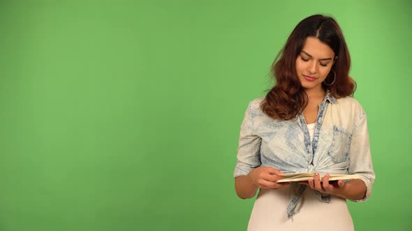 A Young Beautiful Caucasian Woman Reads a Book and Thinks About Something  Green Screen Background