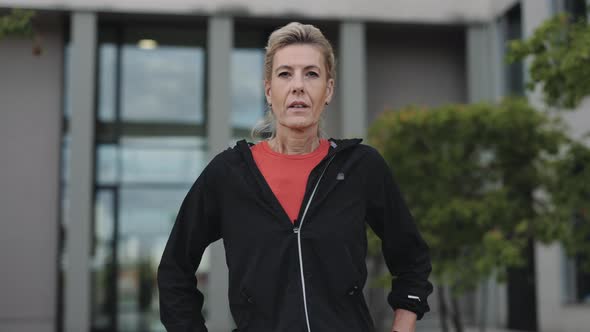 Senior Woman in Active Outfit Resting After Run on Street alt