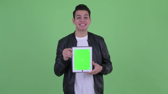 Happy Young Handsome Multi Ethnic Man Showing Digital Tablet and Looking Surprised alt