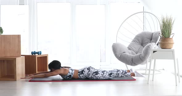 Black woman in sportswear doing workout at home. Fitness concept. alt