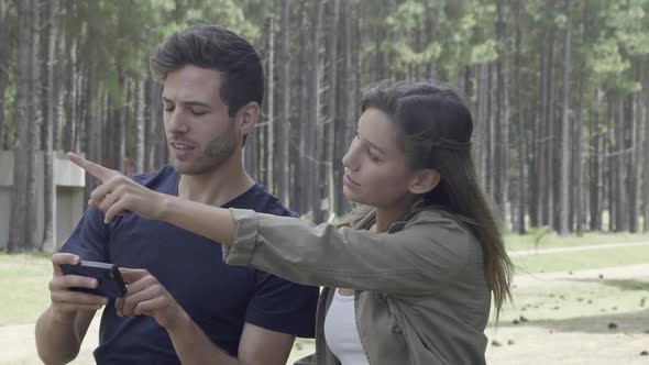 Couple using smart phone to navigate in woods alt