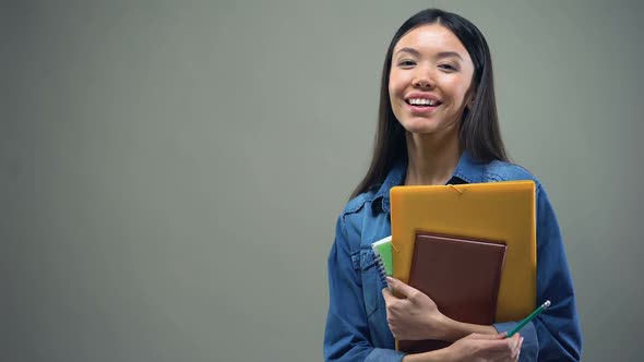 Asian Woman Standing With Copybooks on Grey Background alt