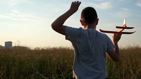 Boy Runs Across the Field and Plays with a Small Airplane at Sunset Slow Motion alt
