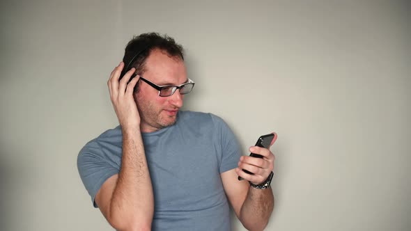 Happy Man Using Mobile Phone While Listening Music on Headphones