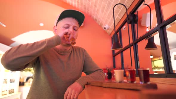 Young Man in a Hat Drinks Strong Alcohol