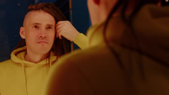 Young Man Looking in Mirror Considering His New Hairstyle alt