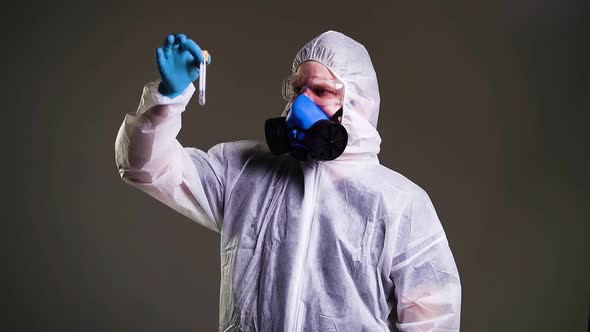 Scientist Virologist in Protective Suit, Goggles and Respirator Holds Test Tube. alt